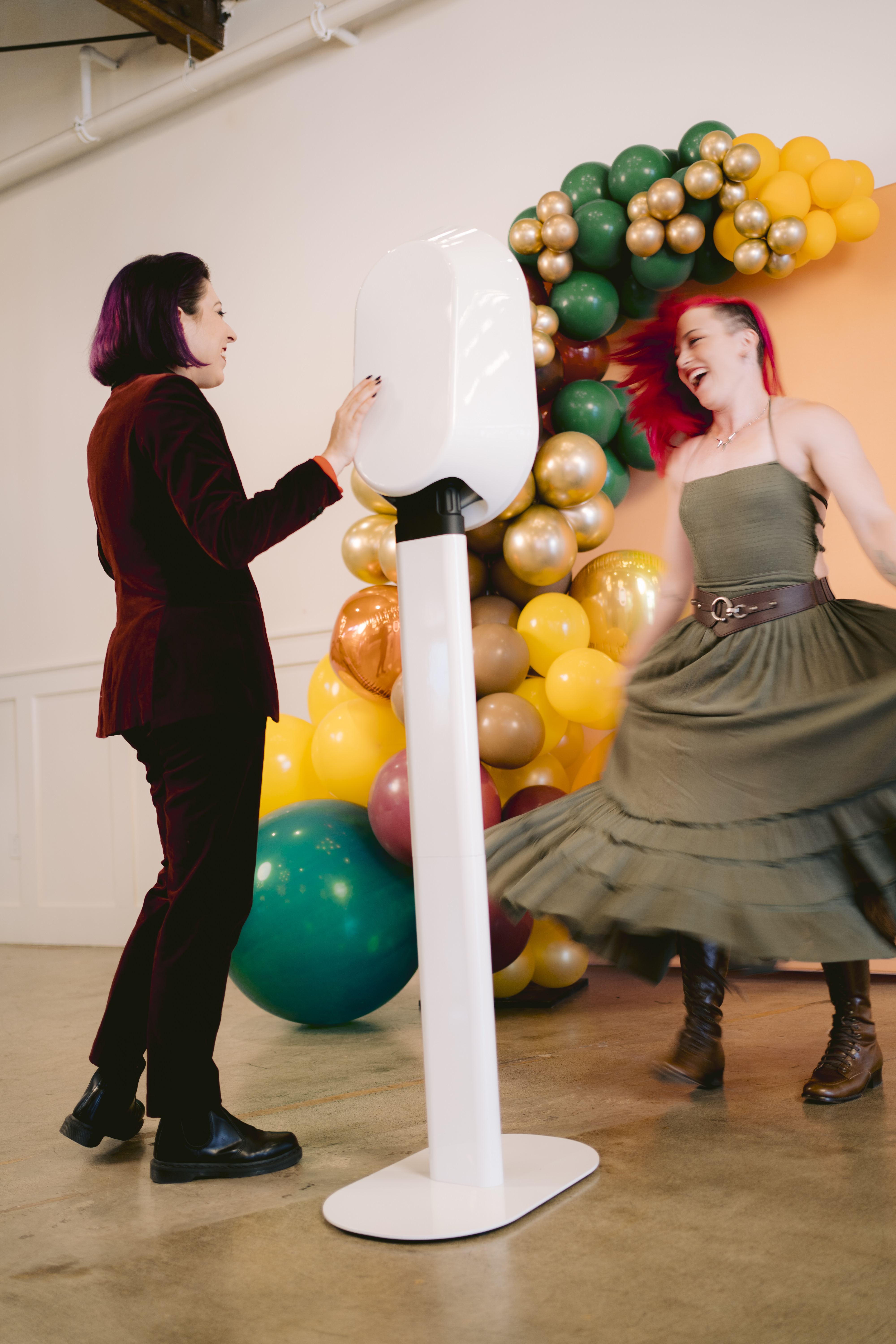 Guests using a white Salsa 2 open-air photo booth at a colorful event setup.