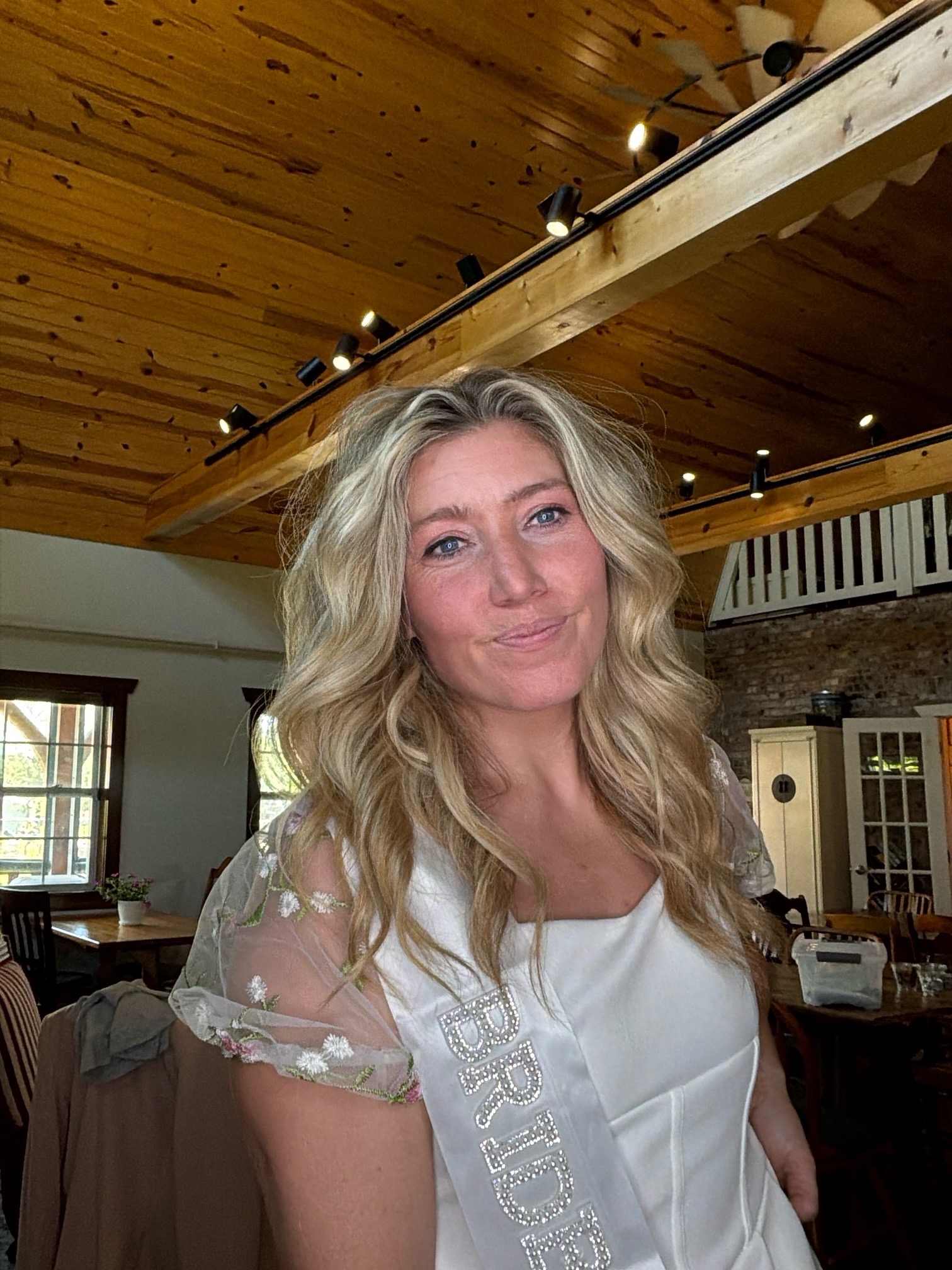 Bride wearing a sash and smiling in a photo booth capture at a private event.